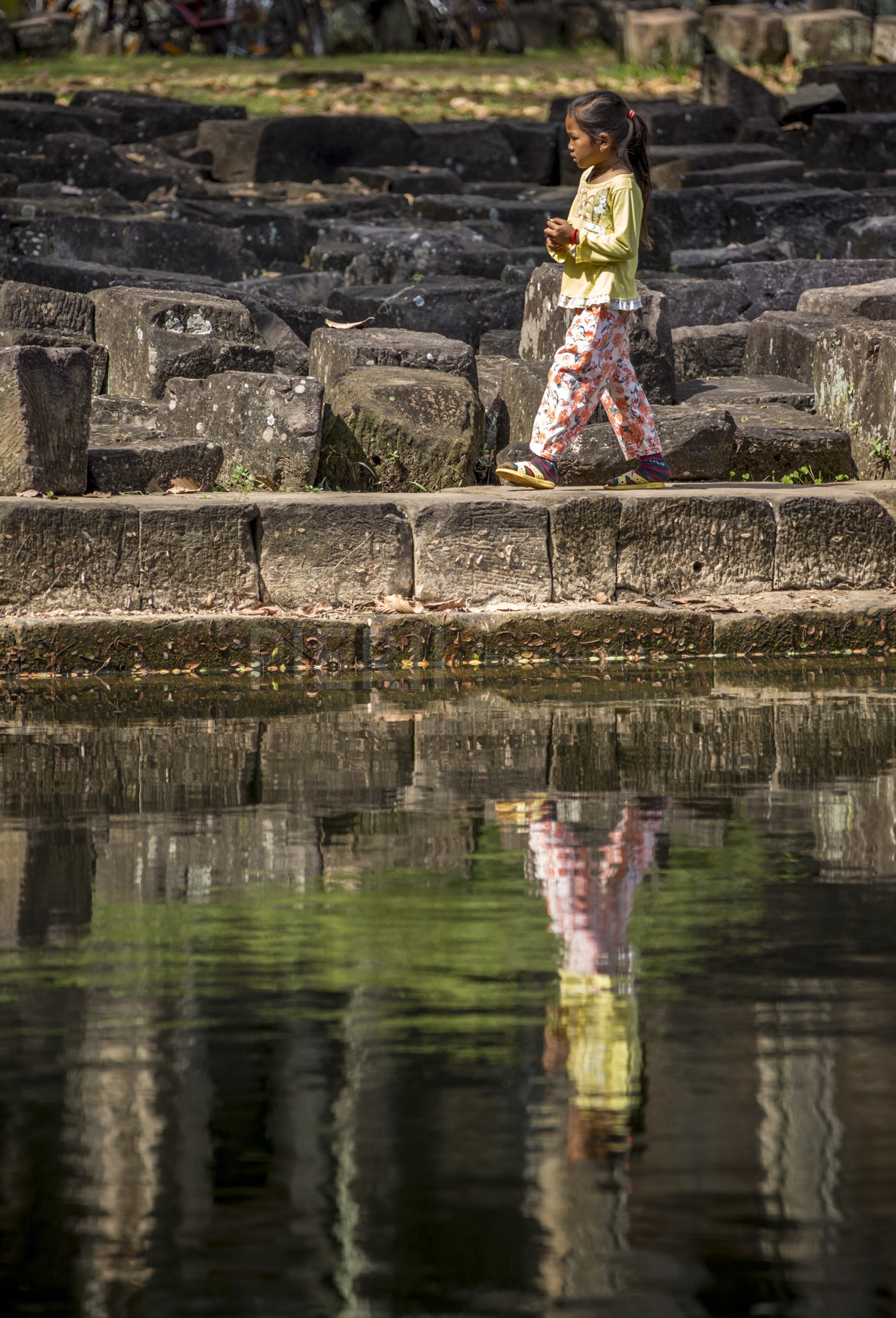 Une enfant marche le long d'un des bassins du temple d'Angkor Wat - A child is walking near a pool of Angkor Wat temple